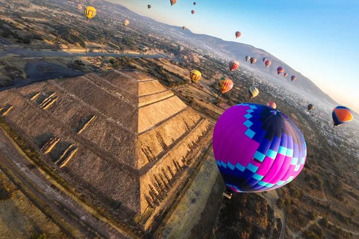 Hot air balloons rising at sunrise over the Pyramid of the Sun at Teotihuacan